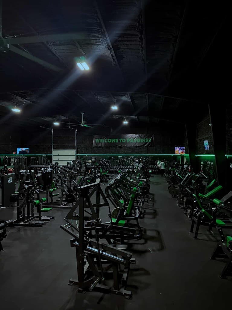 Paradise Gym training floor with neon green equipment and lighting
